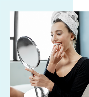 A woman applying aligners in front of a mirror.